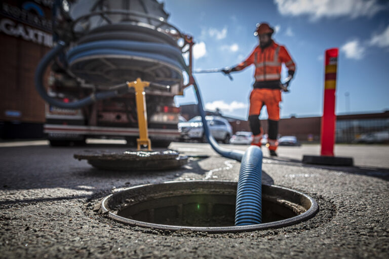 Mies tyhjentää sadevesikaivoa loka-autolla